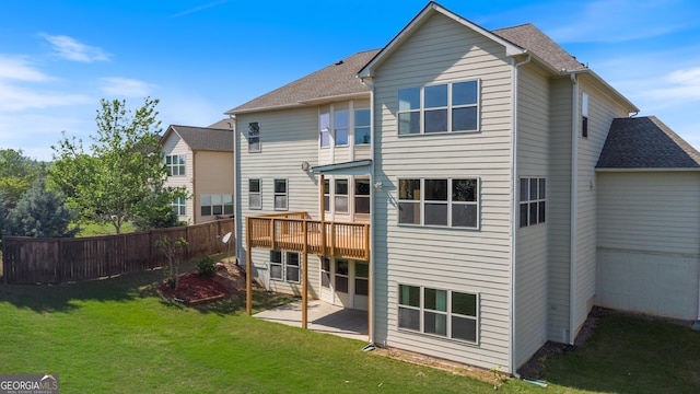 rear view of house with fence, a shingled roof, a yard, a patio, and a deck