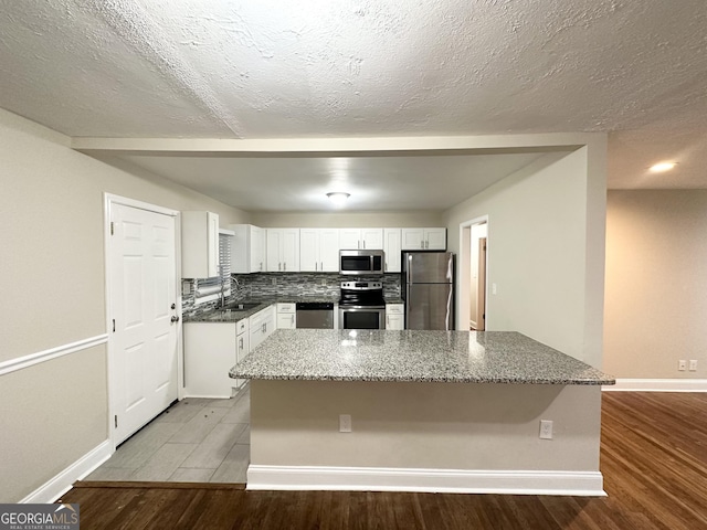 2965 Meadowview Dr SE, Atlanta, GA 30316 - kitchen featuring stainless steel appliances, dark stone countertops, a sink, baseboards, and white cabinetry