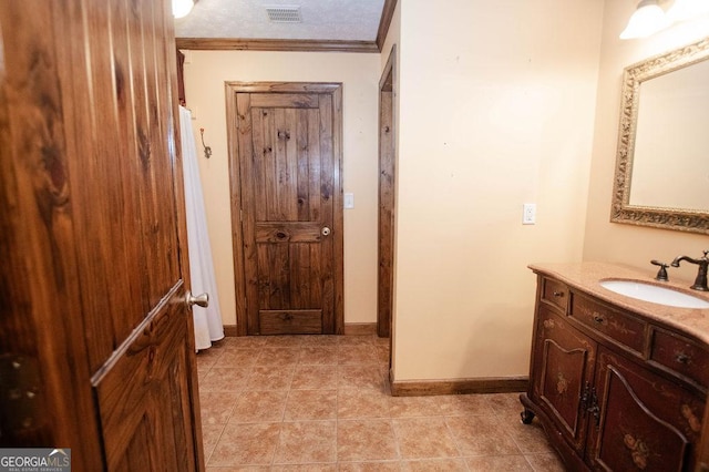 bathroom featuring baseboards, visible vents, tile patterned flooring, vanity, and ornamental molding