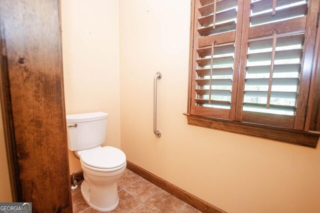 bathroom with baseboards, tile patterned flooring, and toilet
