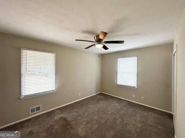 unfurnished room featuring dark carpet, ceiling fan, baseboards, and visible vents