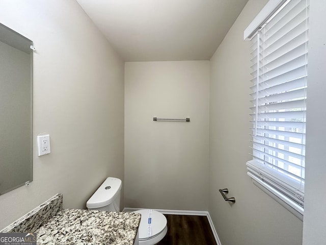 bathroom featuring toilet, wood finished floors, and baseboards