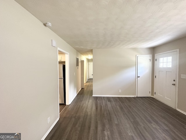 foyer entrance featuring baseboards, dark wood-type flooring, and a textured ceiling