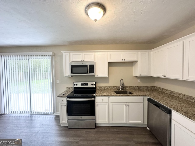 kitchen with white cabinets, dark wood finished floors, appliances with stainless steel finishes, and a sink