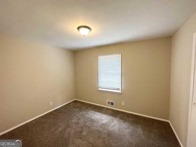 empty room featuring baseboards, dark colored carpet, and visible vents