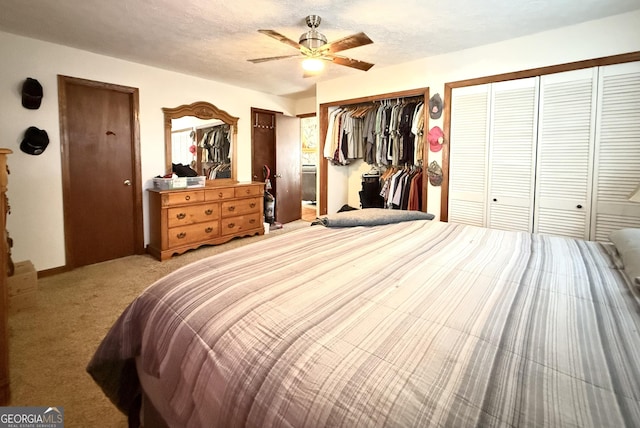 bedroom with light colored carpet, a textured ceiling, multiple closets, and ceiling fan