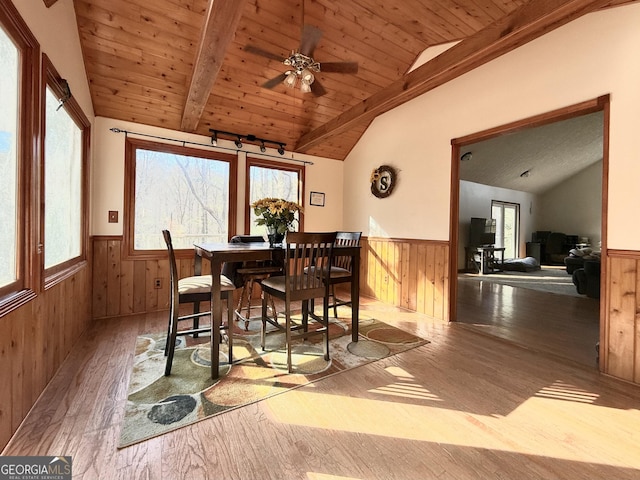 dining space with vaulted ceiling with beams, wood-type flooring, and a wainscoted wall