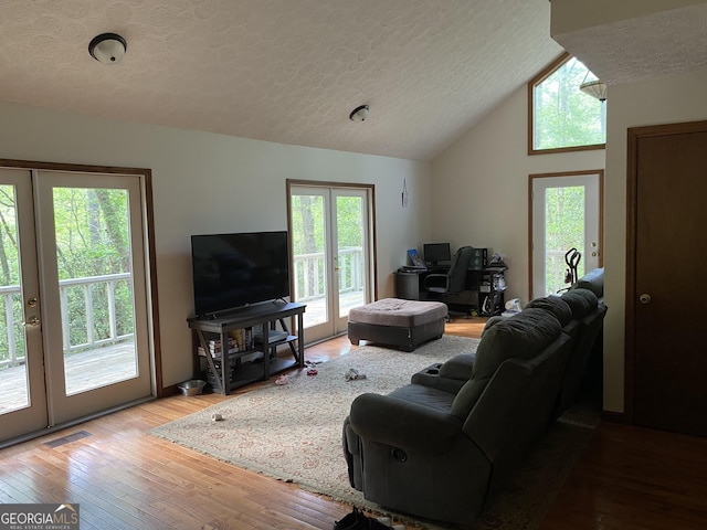 living room with visible vents, a textured ceiling, hardwood / wood-style flooring, and french doors