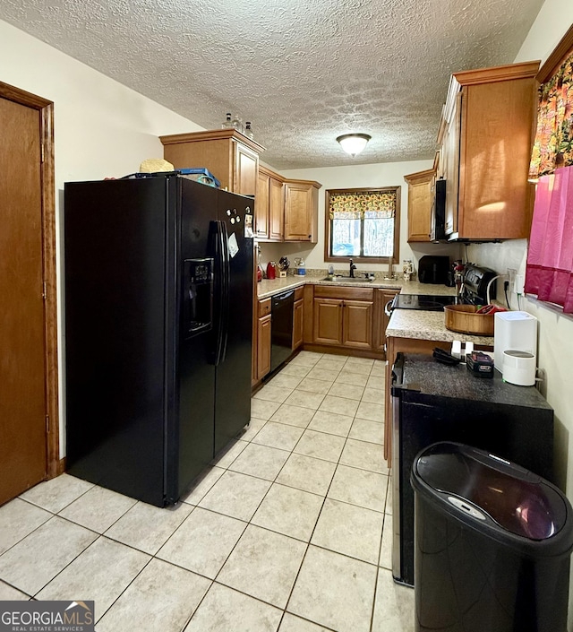 kitchen with light countertops, light tile patterned flooring, a sink, and black appliances