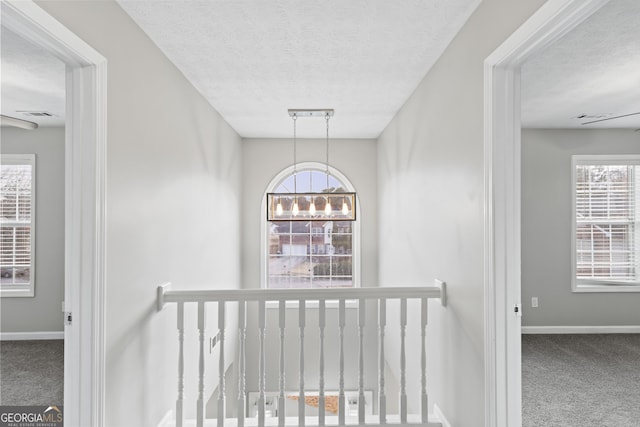 corridor featuring a chandelier, carpet, and an upstairs landing