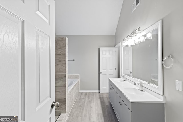 full bathroom with a bath, wood finished floors, visible vents, and a sink