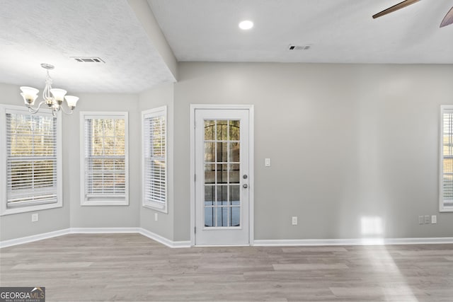 interior space featuring wood finished floors, visible vents, baseboards, and ceiling fan with notable chandelier