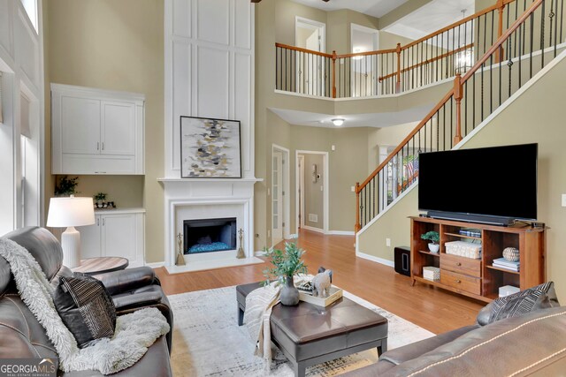 living room featuring stairway, a high ceiling, and light wood-style flooring