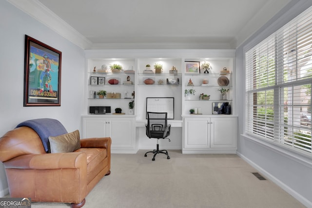 home office with visible vents, built in desk, built in shelves, light colored carpet, and ornamental molding