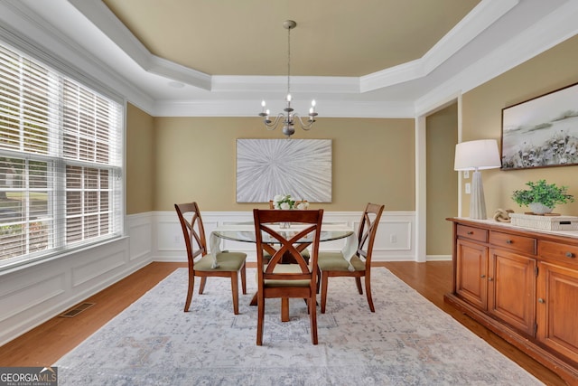 dining room with visible vents, wood finished floors, a notable chandelier, and a raised ceiling