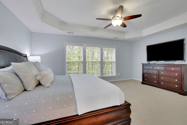 bedroom featuring light carpet, a tray ceiling, visible vents, ceiling fan, and crown molding