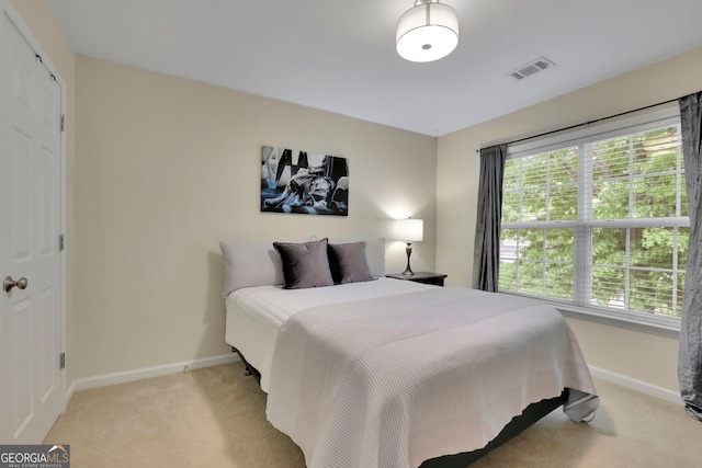 bedroom with baseboards, visible vents, and light colored carpet