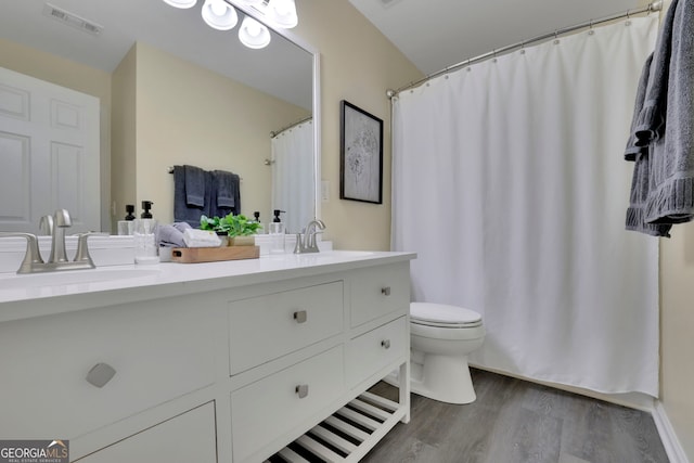 bathroom with double vanity, wood finished floors, visible vents, toilet, and a sink