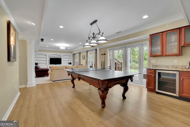 recreation room with light wood-type flooring, ornamental molding, wine cooler, and plenty of natural light