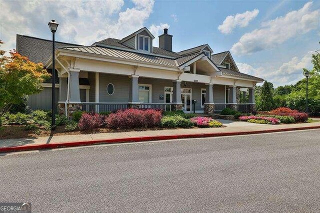 view of front of property with a porch, a standing seam roof, a chimney, and metal roof