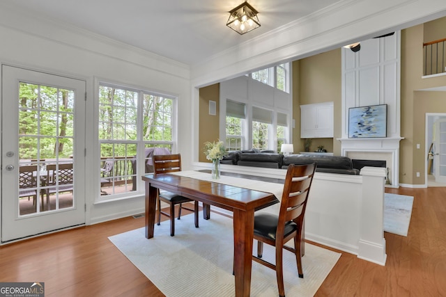 dining room with crown molding, light wood finished floors, and a fireplace