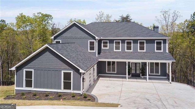 view of front of home featuring a shingled roof, a chimney, and covered porch