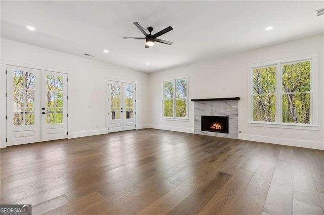 unfurnished living room with ceiling fan, baseboards, french doors, and plenty of natural light
