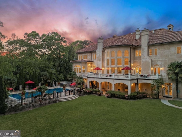 720 Heards Ferry Rd, Atlanta, GA 30328 - back of house at dusk with a fenced in pool, a chimney, a yard, stucco siding, and a patio area