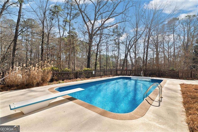 view of pool featuring a fenced in pool, a patio, a fenced backyard, and a diving board