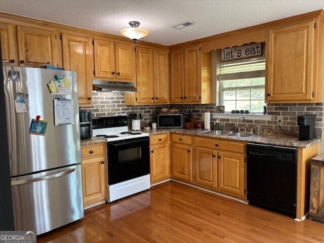 266 W Troutman Rd NE, Rome, GA 30165 - kitchen featuring under cabinet range hood, wood finished floors, a sink, decorative backsplash, and appliances with stainless steel finishes