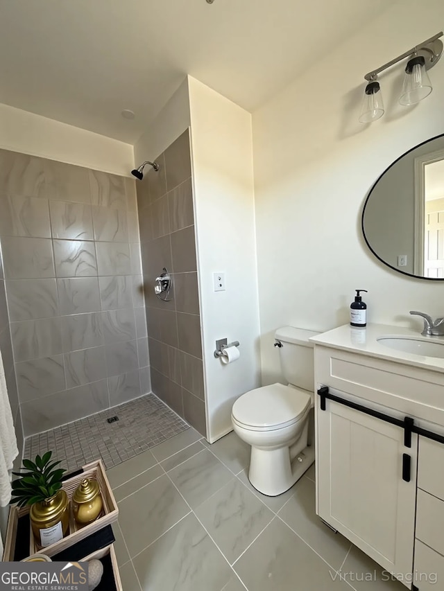 bathroom with toilet, vanity, and tiled shower