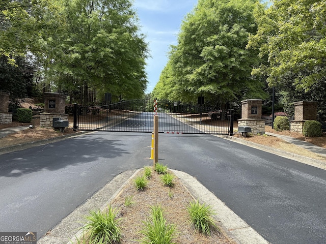view of street with a gate, a gated entry, and curbs