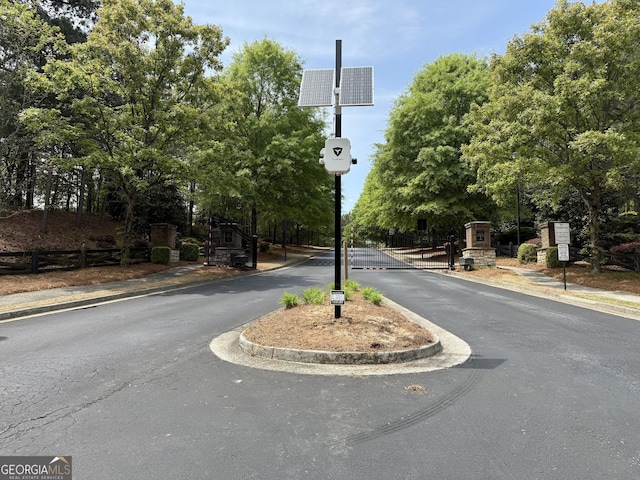 view of street featuring a gate, a gated entry, curbs, and sidewalks