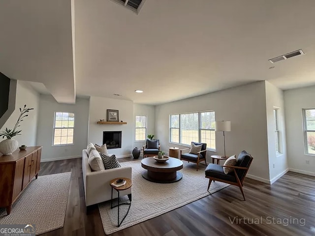 living area with baseboards, visible vents, and dark wood finished floors