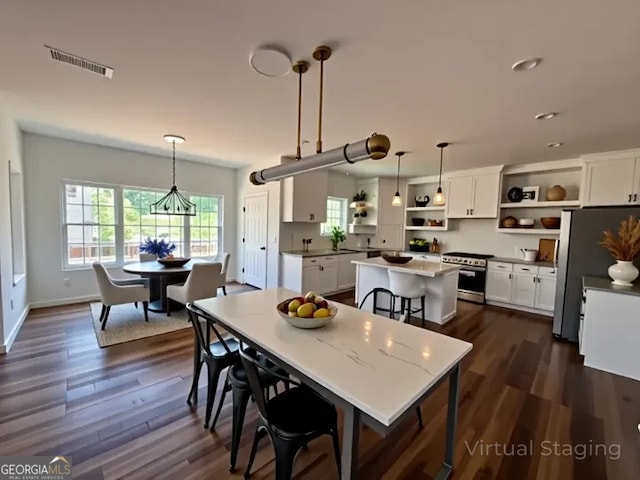 dining space with dark wood-type flooring, an inviting chandelier, visible vents, and a healthy amount of sunlight