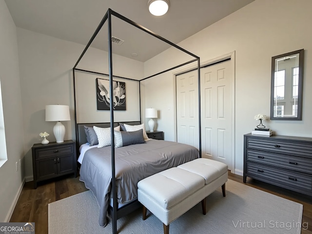 bedroom with baseboards, dark wood-type flooring, visible vents, and a closet