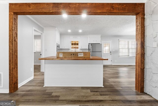 kitchen featuring wooden counters, baseboards, white cabinets, freestanding refrigerator, and dark wood-style floors