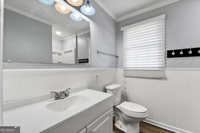 bathroom featuring vanity, ornamental molding, wood finished floors, toilet, and a wainscoted wall