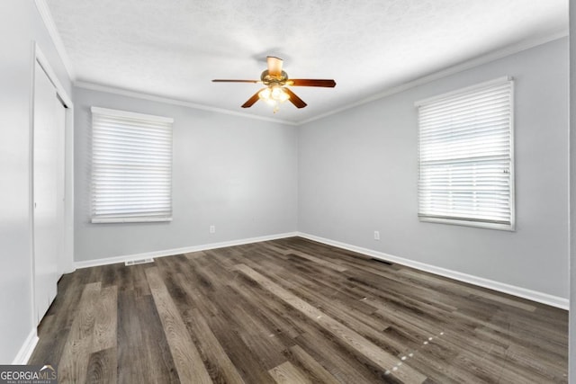 empty room featuring a ceiling fan, visible vents, wood finished floors, baseboards, and ornamental molding