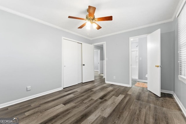 unfurnished bedroom with crown molding, wood finished floors, baseboards, a closet, and ensuite bath
