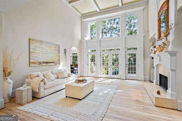 sunroom featuring coffered ceiling, arched walkways, beam ceiling, and french doors