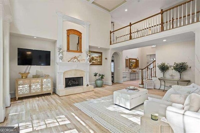 living room with a high ceiling, stairway, a fireplace, baseboards, and wood finished floors