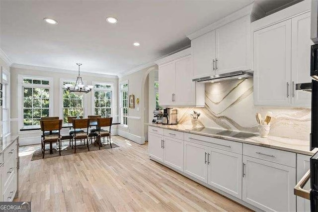 kitchen with black electric cooktop, light wood-style floors, under cabinet range hood, and crown molding