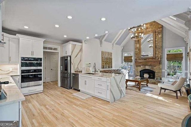 kitchen featuring a sink, stainless steel appliances, a notable chandelier, white cabinetry, and open floor plan