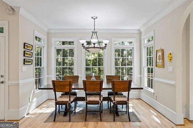 sunroom with arched walkways and a notable chandelier