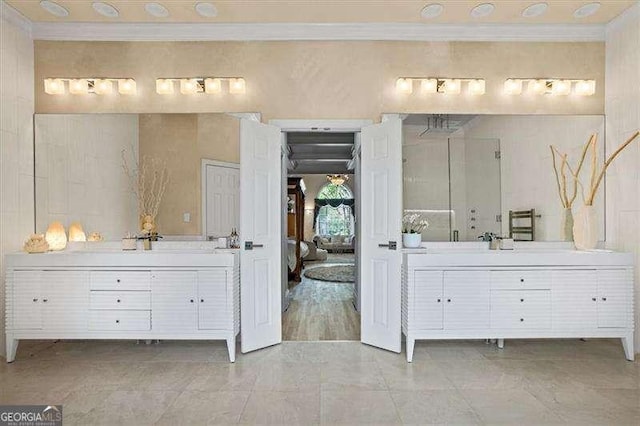 full bathroom featuring ornamental molding and two vanities
