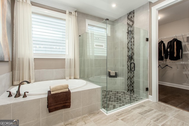 bathroom featuring a bath, a spacious closet, and a stall shower