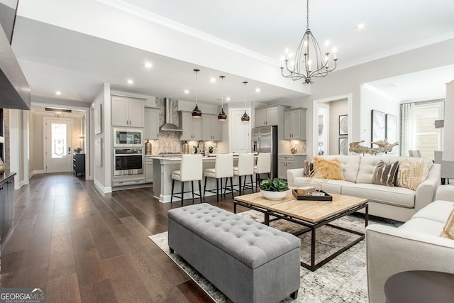 living area featuring crown molding, dark wood-style flooring, a chandelier, and recessed lighting