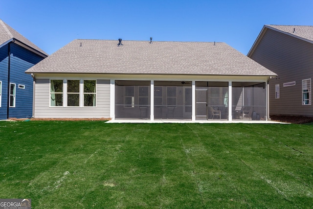 back of property with a yard, roof with shingles, and a sunroom