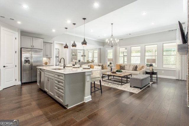 kitchen featuring stainless steel appliances, a breakfast bar, visible vents, a sink, and gray cabinetry